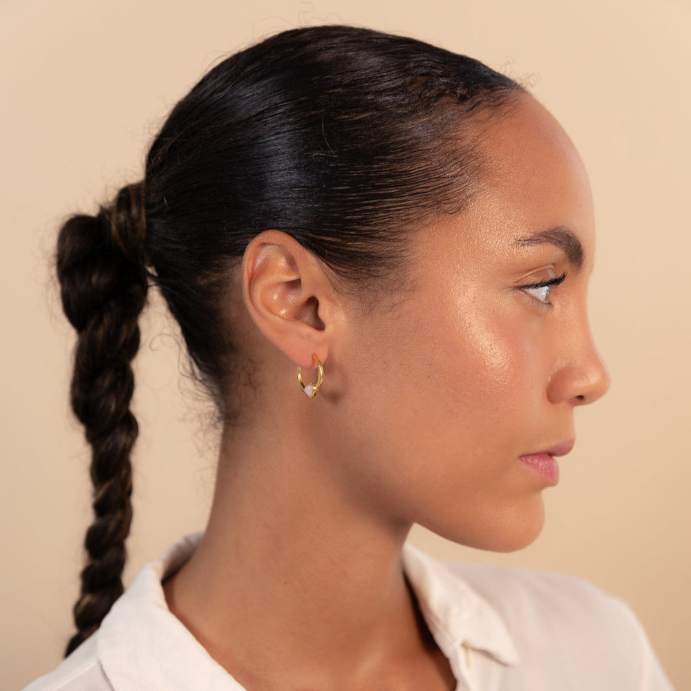 Woman with braided hair wearing a white shirt against a beige background